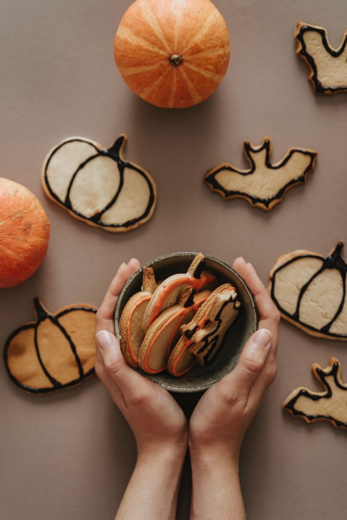 hands around bow of pumpkin cookies low waste Halloween decoration